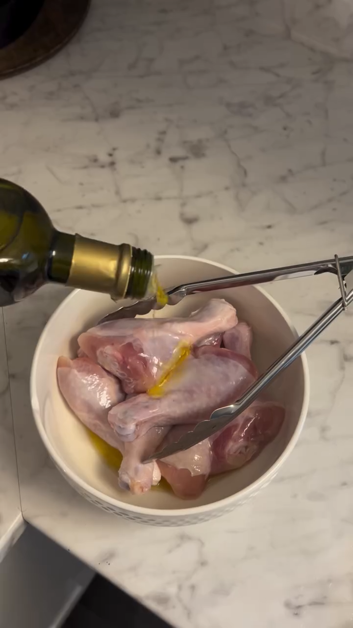 drizzling-olive-oil-on-raw-chicken-drumsticks